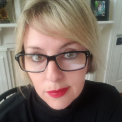 Kelly Rutt headshot - fair-skinned woman, blonde hair, glasses, black shirt