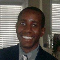 Rodney Machokoto headshot - dark-skinned man, smiling, brown hair, gray collared shirt, tie, black blazer