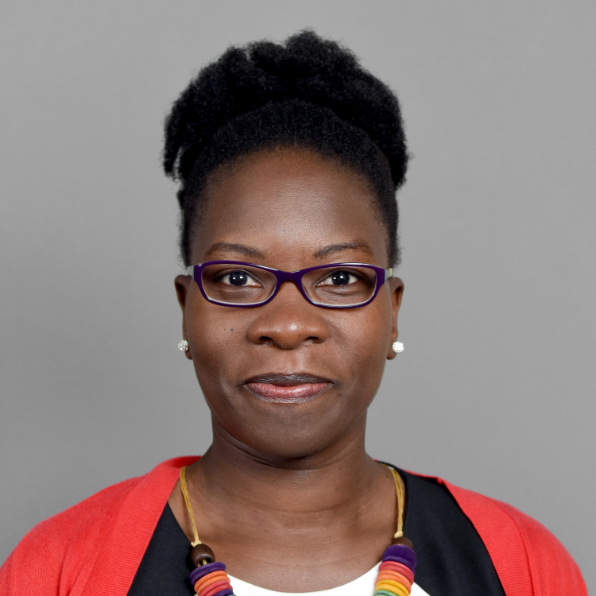 Christine Buzinde headshot - dark-skinned woman, black hair, glasses, black and white shirt, orange cardigan, necklace, earrings